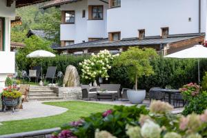 a garden with chairs and tables and umbrellas at Hotel Garni Villa Knauer in Mayrhofen