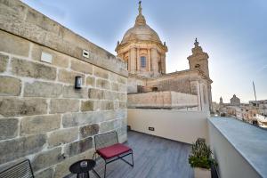 einem roten Stuhl auf dem Balkon eines Gebäudes in der Unterkunft Quaint Boutique Hotel Nadur in Nadur