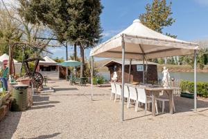 um pavilhão com uma mesa e cadeiras por baixo em Oasis on the river 2 em Marina di Pisa