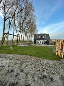 una casa con un parque infantil delante de ella en NIEUW Landelijk vakantiehuis aan zee, en Oostkapelle