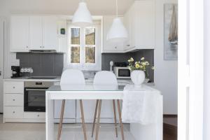 Konstantinos and Eleni's Apartment في Koundouros: مطبخ بدولاب بيضاء وطاولة وكراسي بيضاء