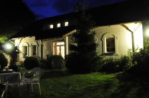 una casa blanca con una silla en el patio por la noche en agroturystyka Orzechowe Wzgórze, en Orzechowo