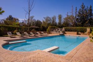 a swimming pool with lounge chairs in a yard at Villa Ferme de Coco in El Caïd Omar