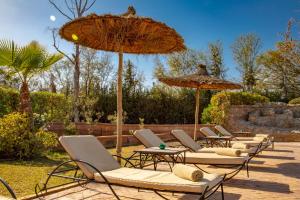 a group of lounge chairs and umbrellas at Villa Ferme de Coco in El Caïd Omar