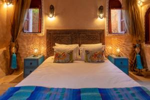 a bedroom with a large bed with two blue night stands at Villa Ferme de Coco in El Caïd Omar