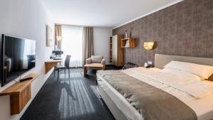 a hotel room with a large bed and a television at Best Western Plus iO Hotel in Eschborn