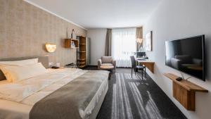 a hotel room with a bed and a flat screen tv at Best Western Plus iO Hotel in Eschborn
