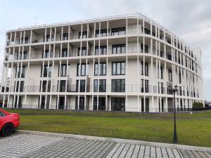 a white building with a red car parked in front of it at Apartament Leśny in Zamość