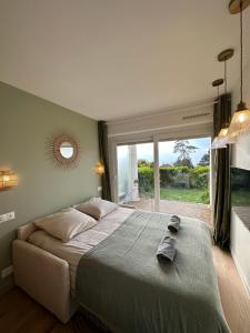 ein Schlafzimmer mit einem großen Bett und einem großen Fenster in der Unterkunft Les Maisons de CharlocHomes, F1 Vue Mer in Trouville-sur-Mer