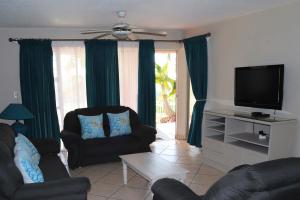 a living room with two chairs and a flat screen tv at Laguna la Crete 66 in Uvongo Beach
