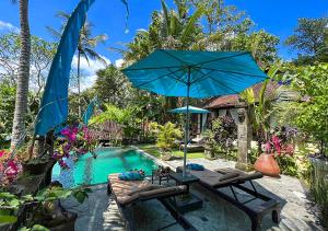 a pool with chairs and an umbrella next to a swimming pool at The Mahogany Villa in Tegalalang