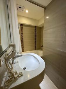 台北的住宿－銀座飯店Ginza Hotel，浴室配有白色水槽和淋浴。