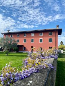 un grand bâtiment rouge avec des fleurs violettes devant lui dans l'établissement Fiori Di Maggio, à Muscletto