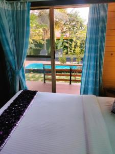 a bedroom with a bed and a large window at Brahmi Resort in Bangalore