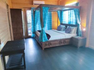 a bedroom with a canopy bed with blue curtains at Brahmi Resort in Bangalore