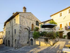 un vecchio edificio in pietra con un ombrello in una strada di Casa Della Torre In Borgo Medievale a Stroncone