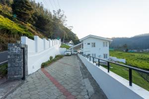 a walkway next to a white building with a fence at lynfields leisure in Ooty