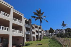 a row of apartment buildings with a palm tree at Laguna la Crete 66 in Uvongo Beach