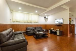 sala de estar con muebles de cuero y TV de pantalla plana en lynfields leisure, en Ooty