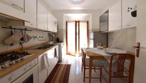 uma cozinha com armários brancos e uma mesa com cadeiras em La casa di Bianca - Casa Vacanze em Villa Opicina