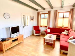 un salon avec un canapé rouge et une télévision dans l'établissement Bummert am Hafen 3 Greetsiel, à Krummhörn