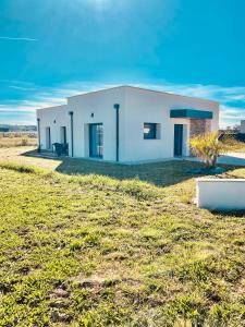 a white house in a field with a grassy field at La Contemporaine in Brax