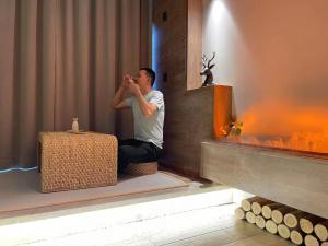 a man sitting on the floor taking a picture in a room at Zac Homestay in Chongqing