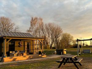 a small cabin with a picnic table in a field at Salnēni in Vecpiebalga