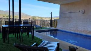 a house with a swimming pool with a table and chairs at Casa con piscina en Parque Nacional de Cabañeros in Navas de Estena