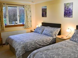 a bedroom with two beds and two windows at Eilean Donan in Kirknewton