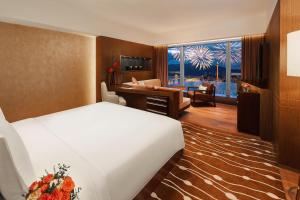 une chambre d'hôtel avec un lit et un salon dans l'établissement Altira Macau, à Macao