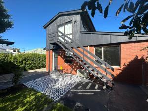 una casa con una escalera en el lateral de ella en Beckenham Studio on tree lined street, en Christchurch