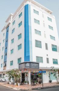 un gran edificio blanco con un restaurante frente a él en White Corner Hotel en Phnom Penh