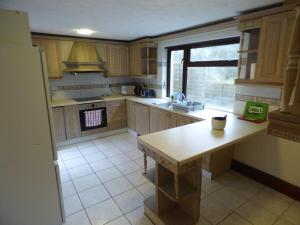 a kitchen with wooden cabinets and a table in it at The Mill Cottage in Llechryd