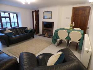 a living room with leather furniture and a table with a fireplace at The Mill Cottage in Llechryd