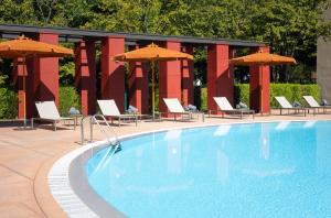 a swimming pool with chairs and umbrellas at Disney Hotel New York - The Art of Marvel in Chessy