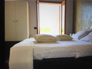 a white bed with two pillows on it with a window at Villa Il Cappero in San Vito lo Capo