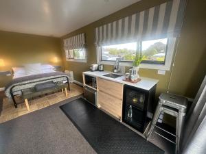 a small kitchen with a sink and a bed at Beckenham Studio on tree lined street in Christchurch