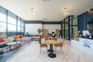 a lobby with tables and chairs in a building at Gangneung Chonpines Ocean Suites Hotel in Gangneung