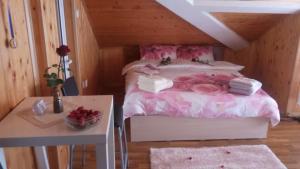 Un dormitorio con una cama con sábanas rosas y una mesa. en Green Loft Apartment-Rose, en Sliven