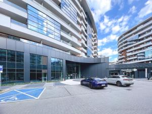 twee auto's geparkeerd op een parkeerplaats voor een gebouw bij Vistula Riverside Apartment in Krakau