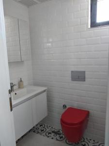a white bathroom with a red toilet and a sink at Sakın bir ortamda 3 odalı villa in Antalya