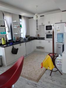 a kitchen with white cabinets and red chairs in it at Sakın bir ortamda 3 odalı villa in Antalya