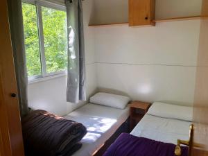 Habitación pequeña con 2 camas y ventana en Camping Aigües Braves, en Llavorsí