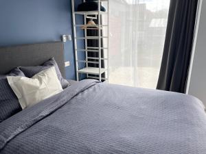 ein Schlafzimmer mit einem Bett und einem Fenster mit einem Regal in der Unterkunft Tiny House in Limburg bij Kelly & Nick in Ham