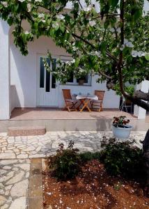 a patio with a table and chairs under a tree at Rooms Hodanić in Krk