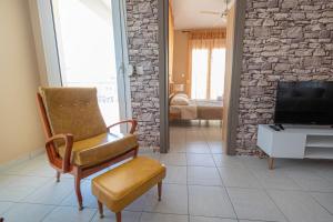 een woonkamer met een stoel en een televisie bij Antonia Apartment by RentalsPro- Nea Moudania Halkidiki in Nea Moudania