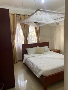 1 dormitorio con cama con dosel y ventana en Golden Cherries Guest House, en Jinja