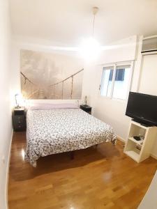 ムルシアにあるAPARTAMENTO PATRICIAの白いベッドルーム(ベッド1台、テレビ付)