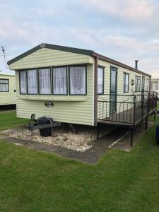 a green mobile home with a porch on the grass at Sws Coral Beach 3 bedroom sleeps 6 in Ingoldmells